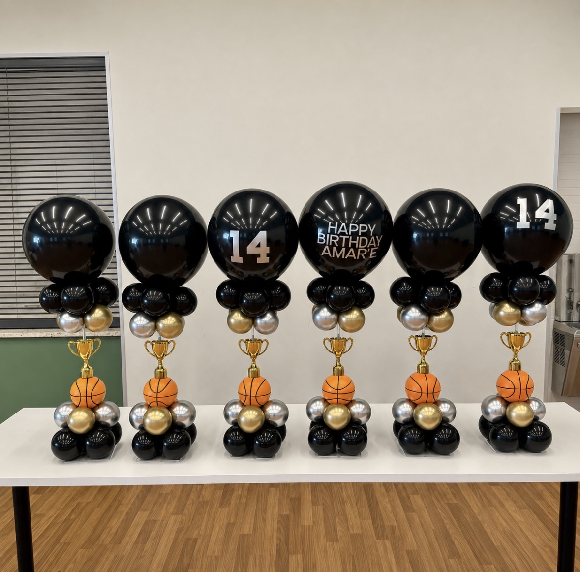A coordinated collection of black, gold, and silver basketball balloon centerpieces
