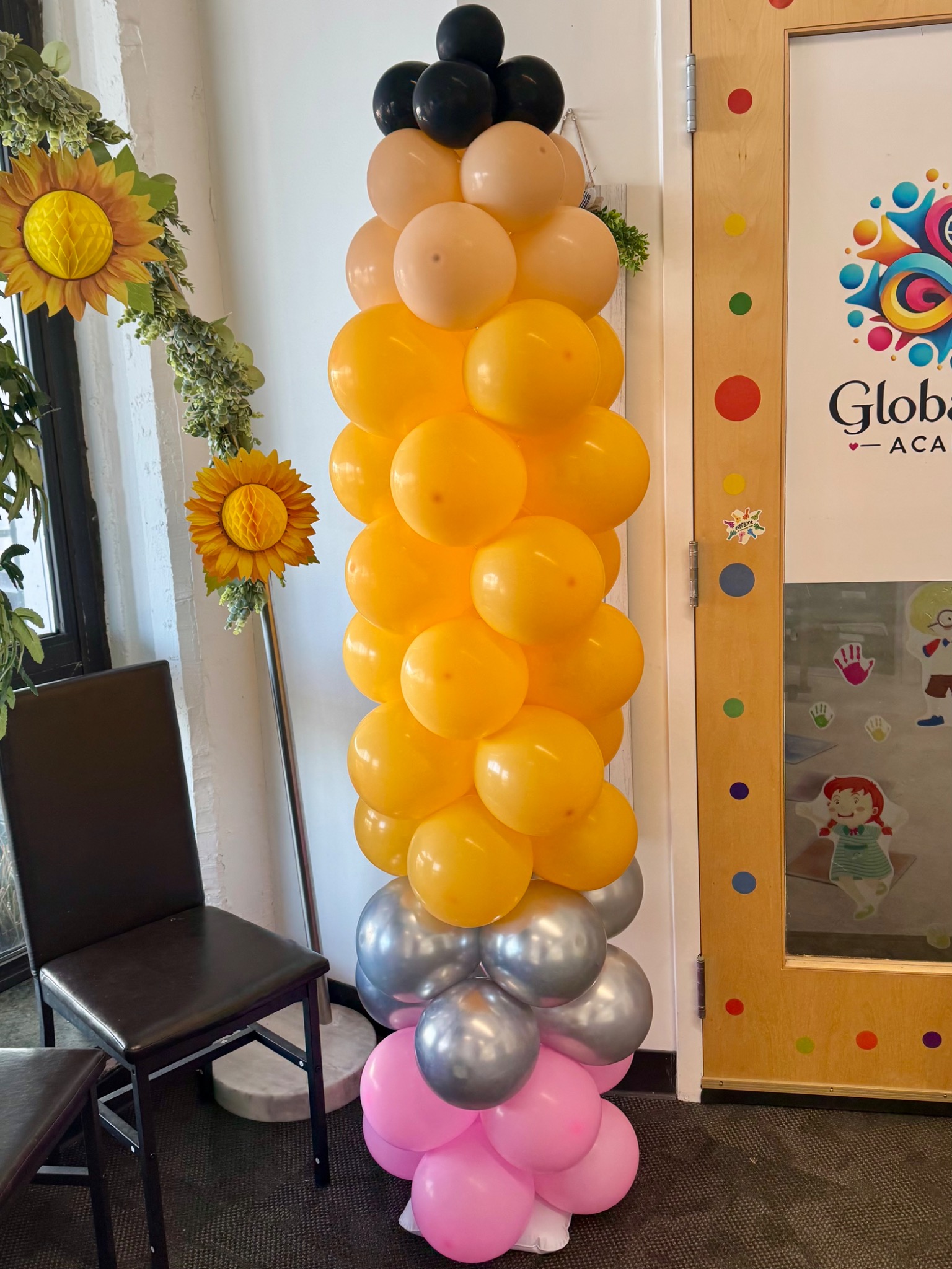 Tall yellow pencil balloon column with a colorful balloon base